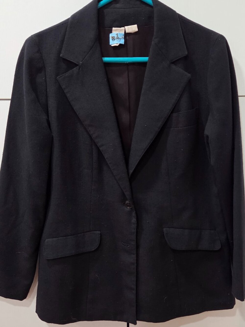 Classic black single-button blazer featuring notched lapels and...